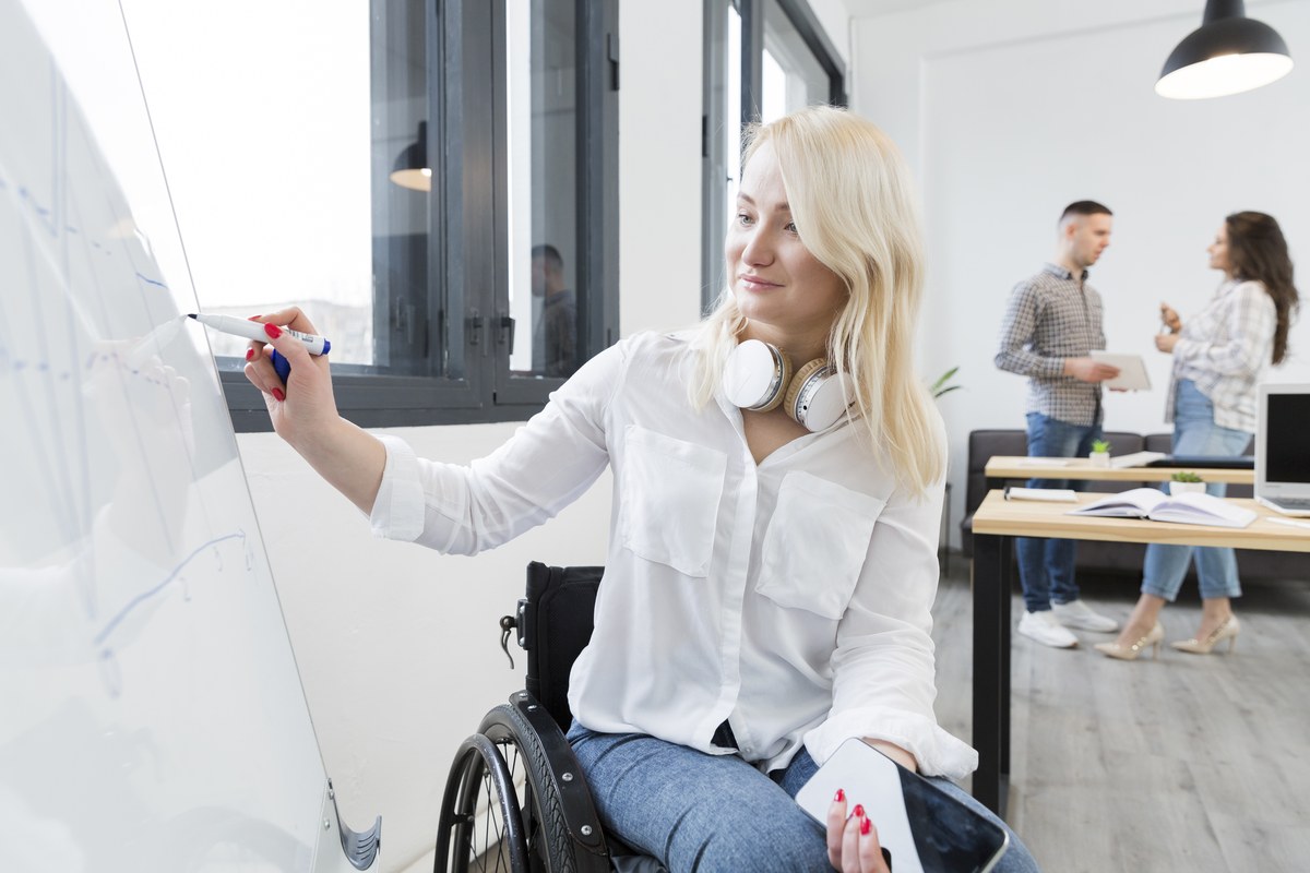 Een zelfverzekerde vrouw in een rolstoel die actief meewerkt op een whiteboard op kantoor