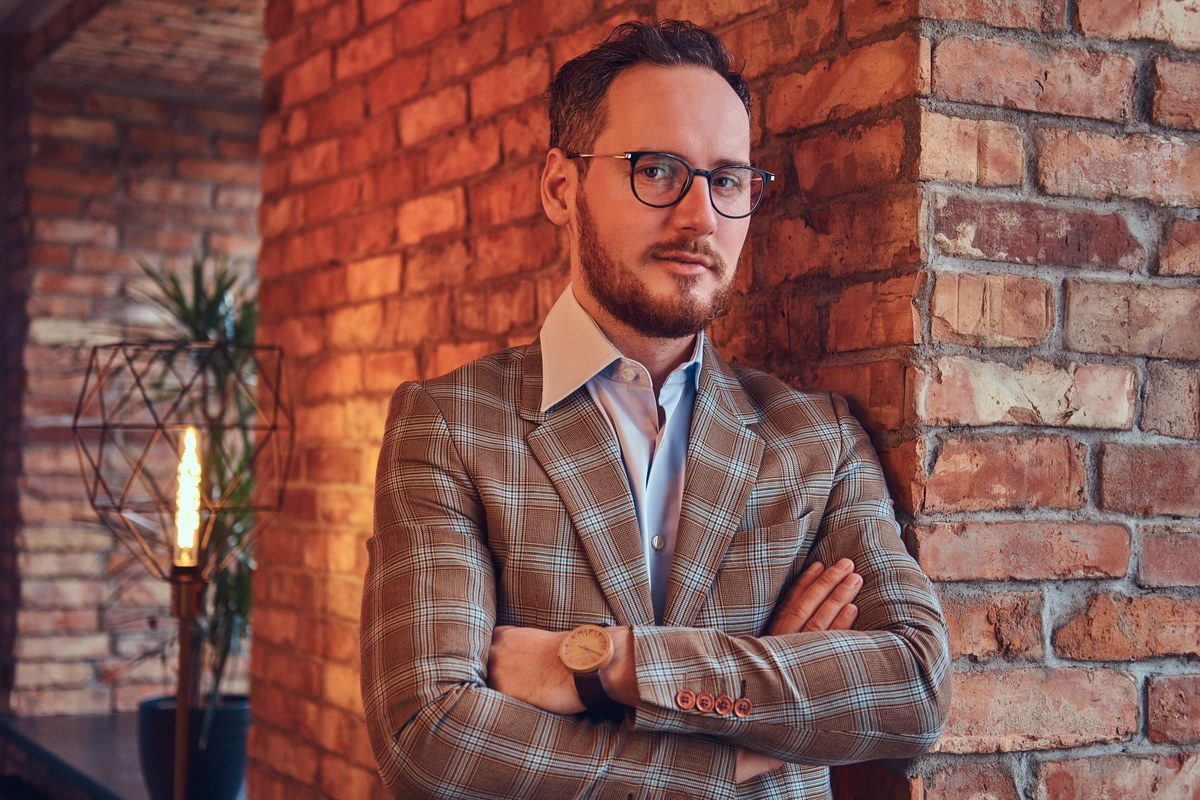 Portret van een zelfverzekerde zelfstandige ondernemer met gekruiste armen tegen een bakstenen muur