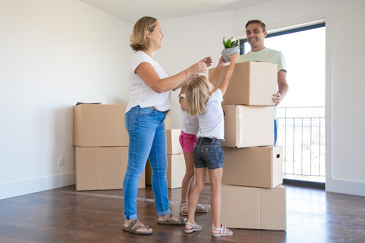 Een jong gezin dat samen dozen uitpakt in de woonkamer van hun nieuwe huis