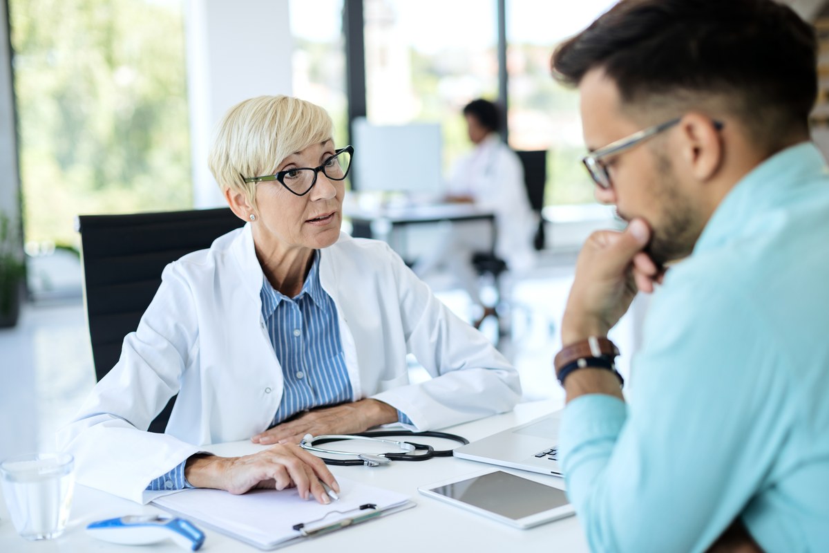 Een dokter bespreekt medische gegevens rustig met een patiënt in een lichte, moderne praktijk